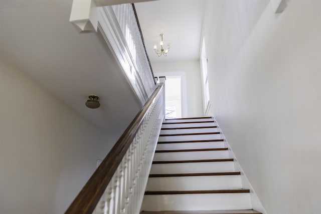 stairs featuring a chandelier