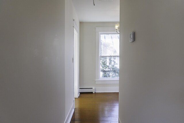 hallway featuring an inviting chandelier, a baseboard heating unit, and dark wood-type flooring