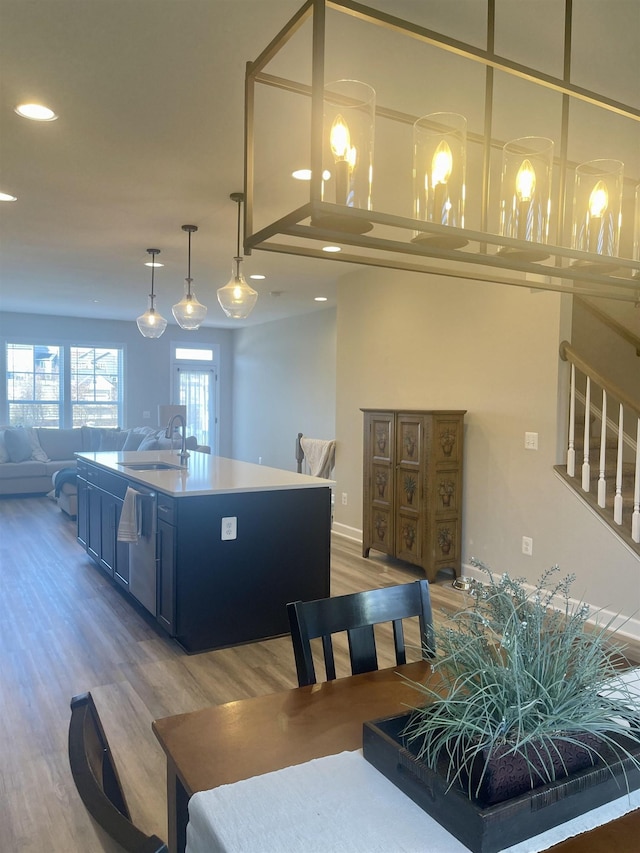 kitchen featuring a center island with sink, hardwood / wood-style flooring, stainless steel dishwasher, pendant lighting, and sink