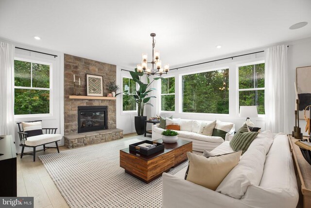 living room with a fireplace, light hardwood / wood-style floors, and a notable chandelier