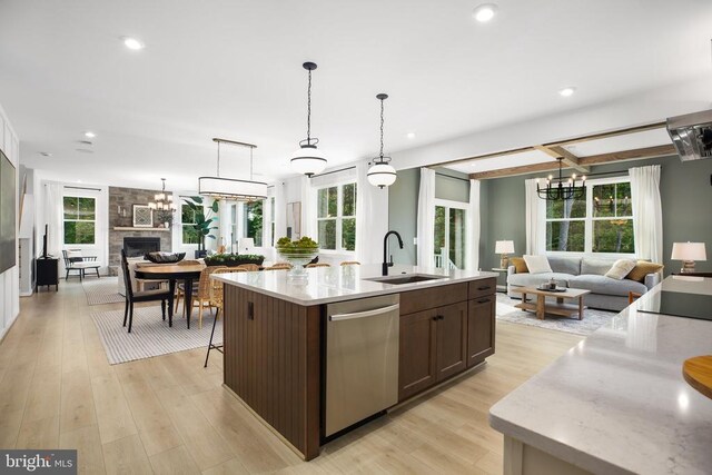 kitchen featuring pendant lighting, sink, dark brown cabinets, an island with sink, and stainless steel dishwasher