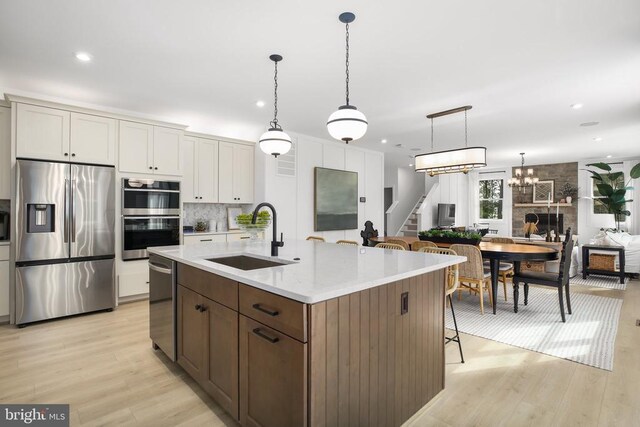 kitchen with an island with sink, appliances with stainless steel finishes, sink, and white cabinets