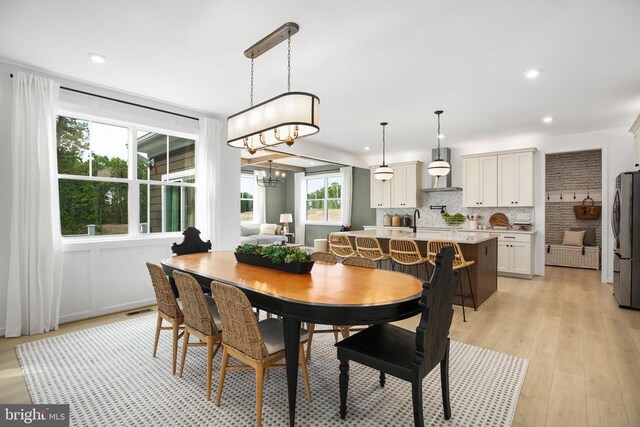 dining space with an inviting chandelier, sink, and light wood-type flooring