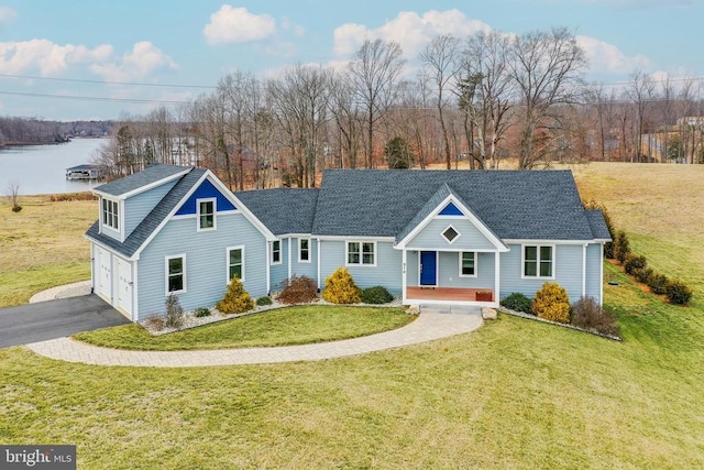 view of front of property with roof with shingles, a water view, an attached garage, driveway, and a front lawn