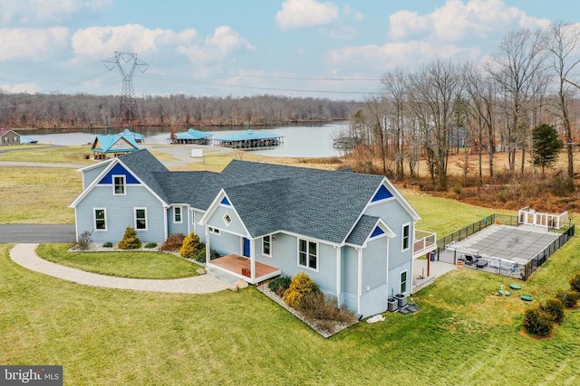 exterior space with driveway, a shingled roof, a water view, and a front yard