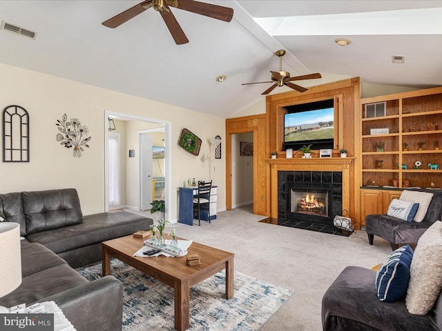 living room with light carpet, vaulted ceiling with beams, a tile fireplace, and ceiling fan