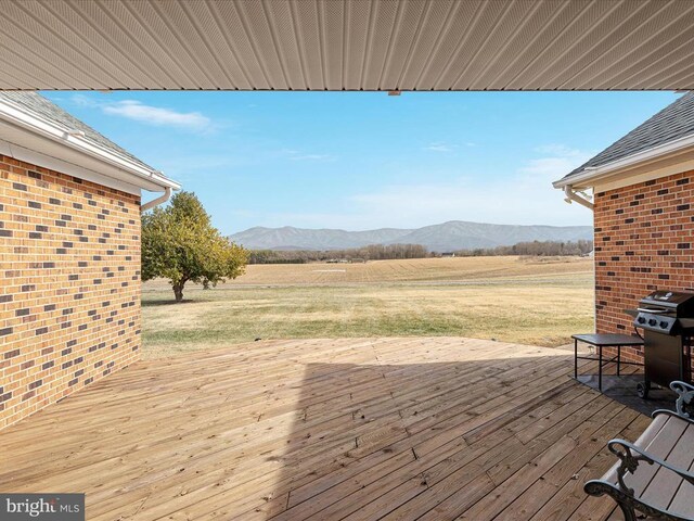 wooden deck with a rural view, a mountain view, and grilling area