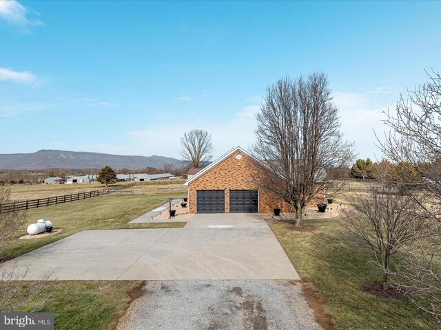 exterior space with a garage, a mountain view, a lawn, and a rural view