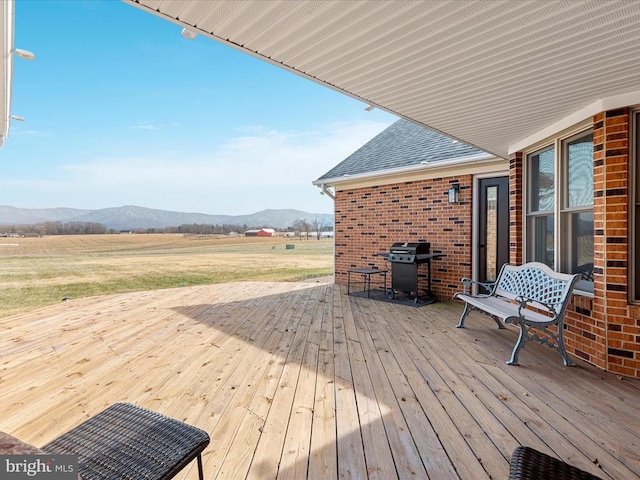 wooden deck featuring a rural view, a mountain view, and grilling area