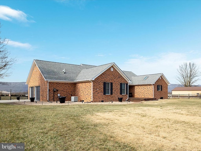 rear view of property with central AC, a yard, and a garage