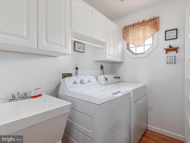 laundry area with dark hardwood / wood-style flooring, sink, washing machine and dryer, and cabinets