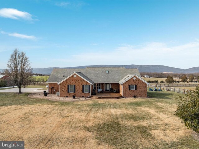 view of front of home featuring a deck with mountain view, a front lawn, and a rural view