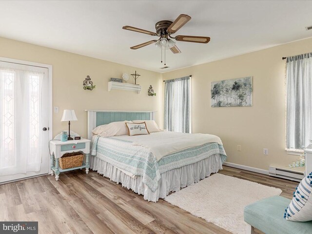 bedroom featuring multiple windows, a baseboard heating unit, and hardwood / wood-style flooring