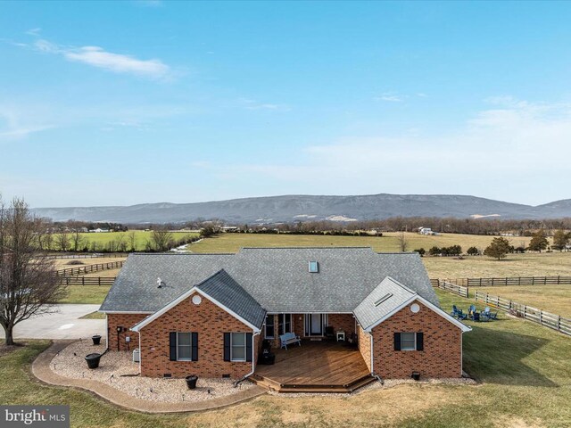 exterior space featuring a deck with mountain view, a lawn, and a rural view