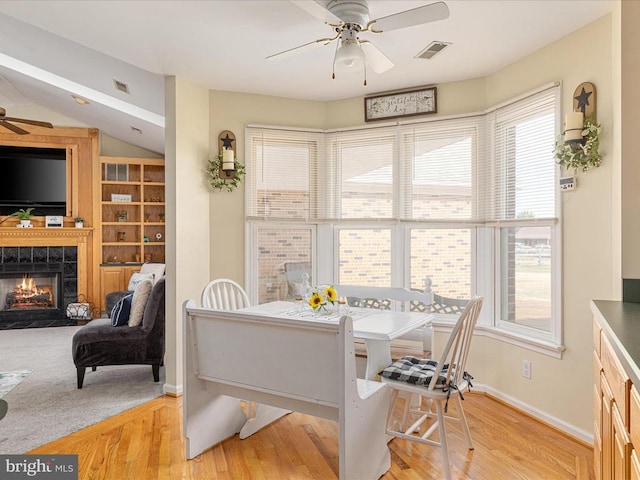 dining area with light hardwood / wood-style flooring, a fireplace, a wealth of natural light, and ceiling fan