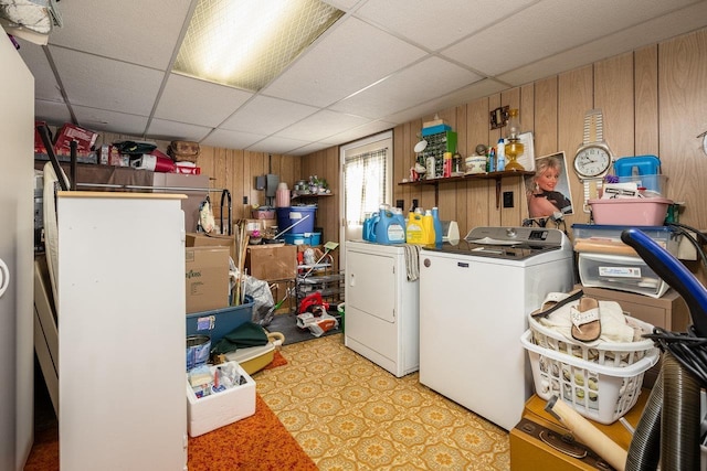 clothes washing area featuring separate washer and dryer and wood walls