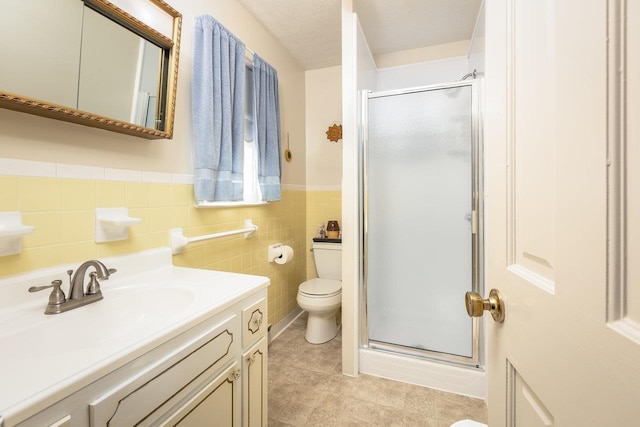 bathroom with a shower with shower door, tile walls, vanity, toilet, and a textured ceiling