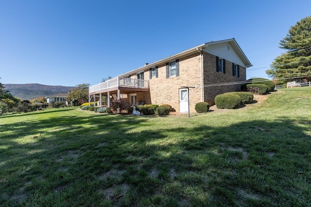 rear view of house with a mountain view and a lawn