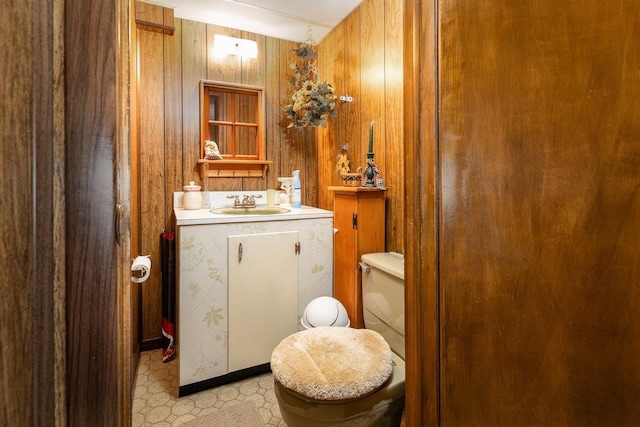 bathroom with vanity, toilet, and wood walls