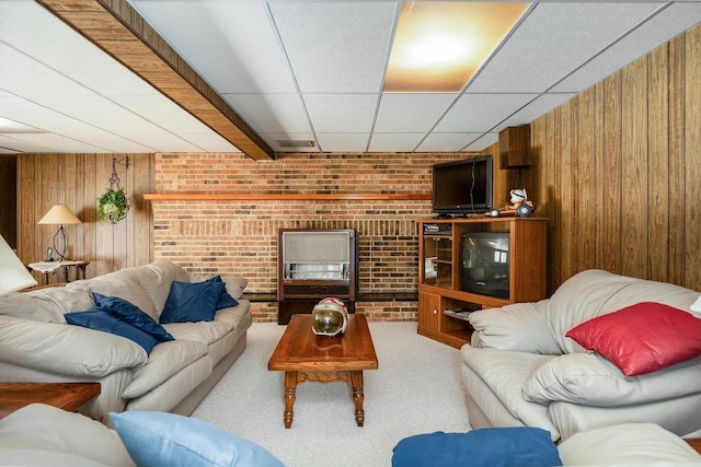 living room with a paneled ceiling, wood walls, brick wall, and carpet