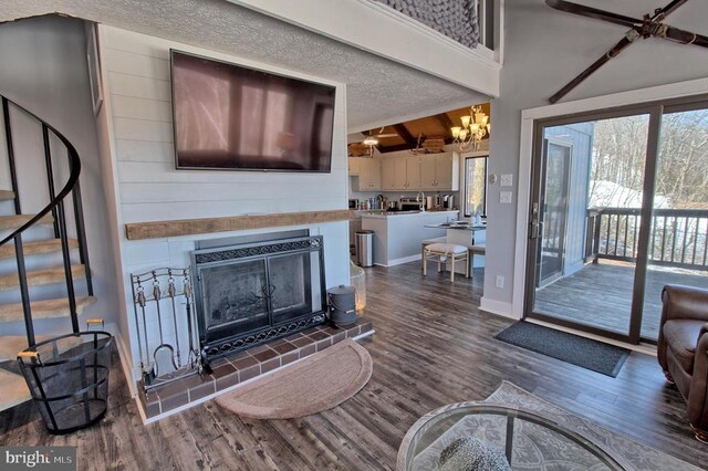 living room with dark wood-type flooring, a tiled fireplace, a textured ceiling, and a wealth of natural light