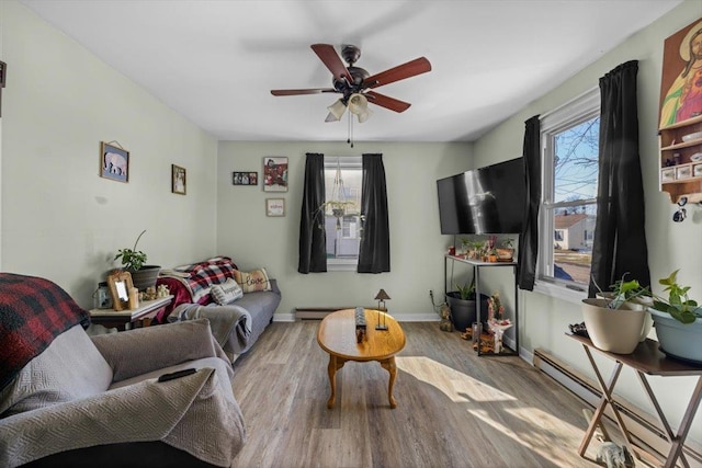 living room featuring ceiling fan, a healthy amount of sunlight, baseboard heating, and light hardwood / wood-style flooring