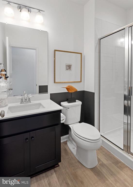 bathroom with walk in shower, wood-type flooring, toilet, and vanity