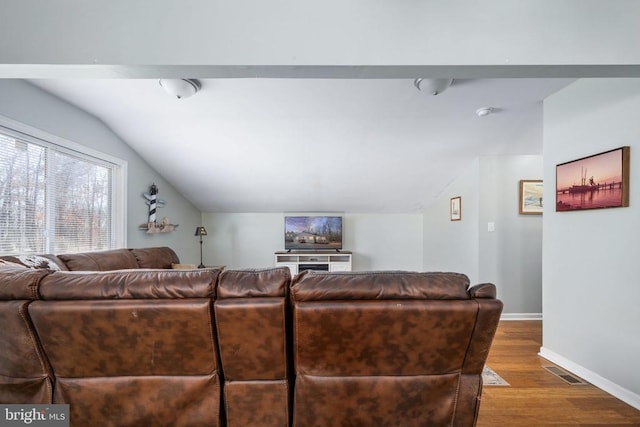 living room with visible vents, vaulted ceiling, baseboards, and wood finished floors