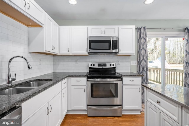 kitchen with appliances with stainless steel finishes, white cabinets, and a sink