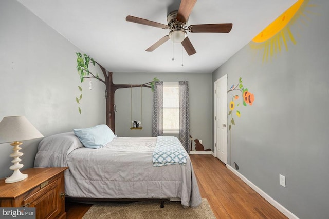 bedroom featuring a ceiling fan, baseboards, and wood finished floors