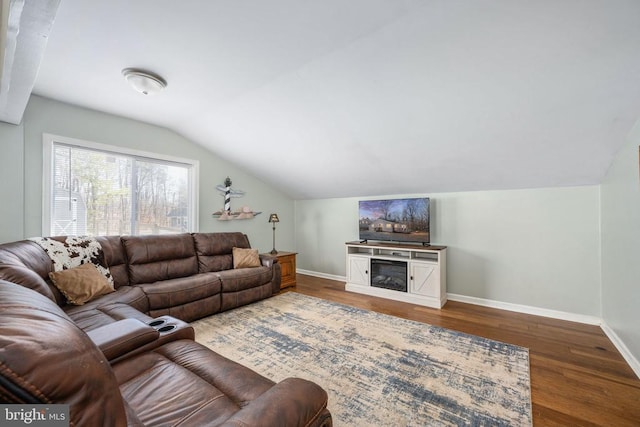 living room featuring lofted ceiling, a fireplace, baseboards, and wood finished floors