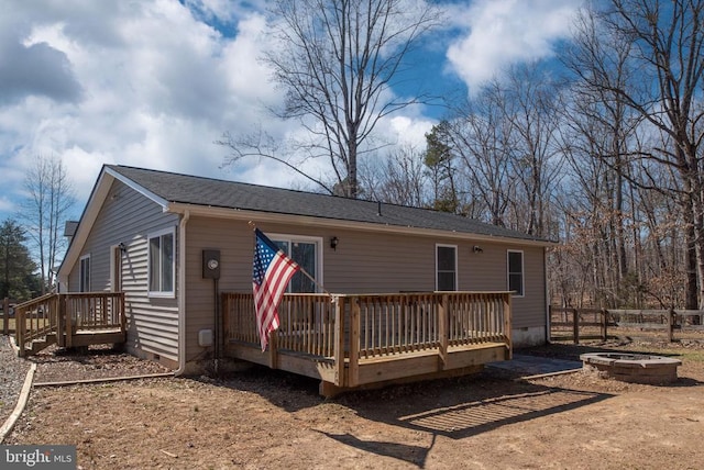 view of front facade featuring a deck, crawl space, a fire pit, and fence