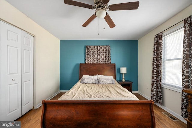 bedroom with a ceiling fan, baseboards, visible vents, and wood finished floors