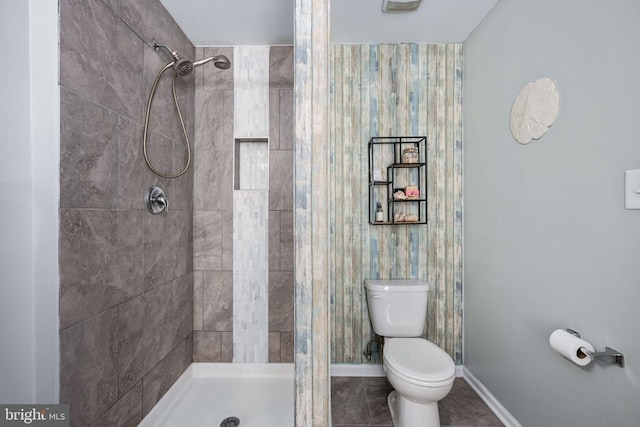 bathroom with toilet, a shower stall, and baseboards