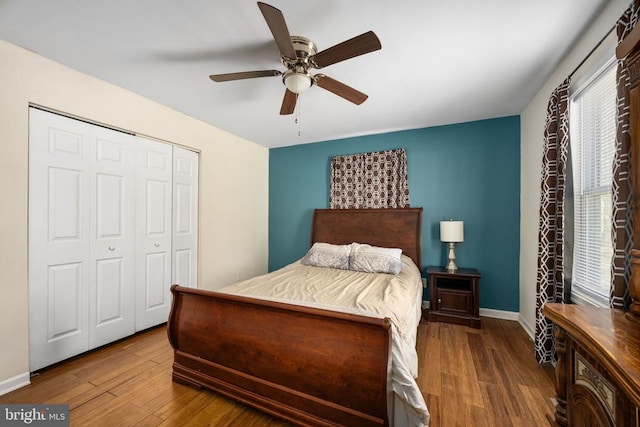 bedroom featuring ceiling fan, a closet, baseboards, and wood finished floors