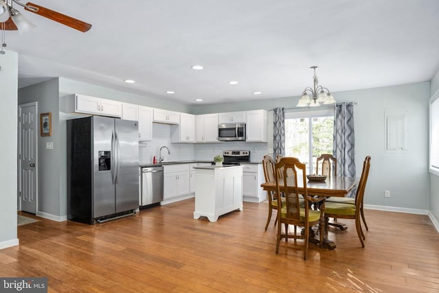 kitchen featuring wood finished floors, white cabinetry, baseboards, appliances with stainless steel finishes, and backsplash