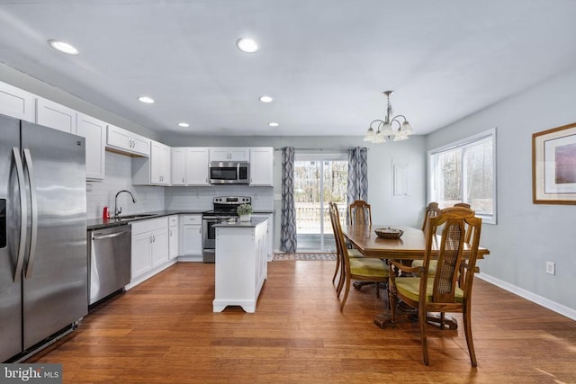 kitchen with white cabinets, dark wood finished floors, decorative backsplash, stainless steel appliances, and a sink