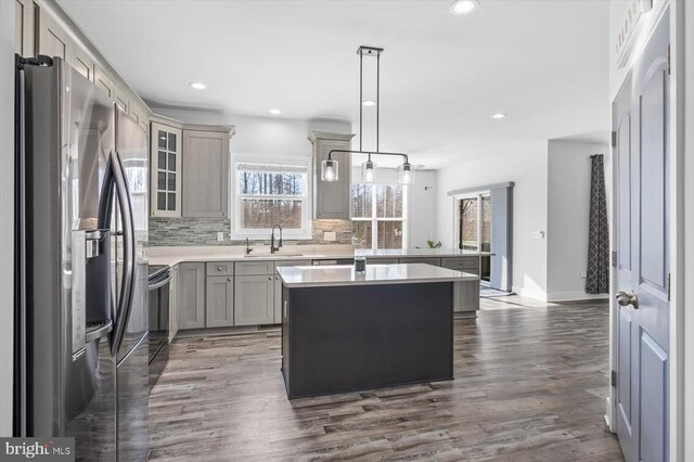 kitchen featuring electric stove, tasteful backsplash, a kitchen island, stainless steel fridge with ice dispenser, and decorative light fixtures