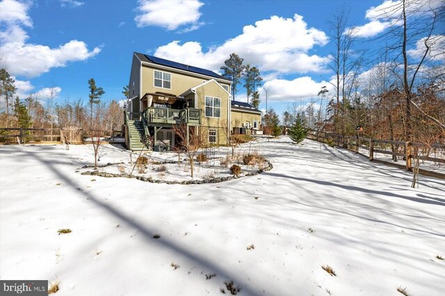 snow covered back of property with a deck