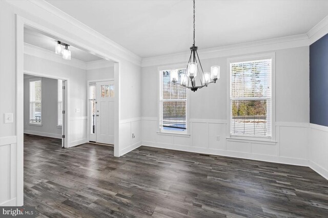 unfurnished dining area featuring crown molding, dark hardwood / wood-style flooring, and a chandelier