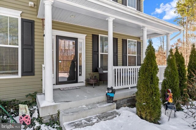 snow covered property entrance with covered porch