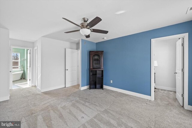 unfurnished bedroom featuring light carpet, ceiling fan, and ensuite bath