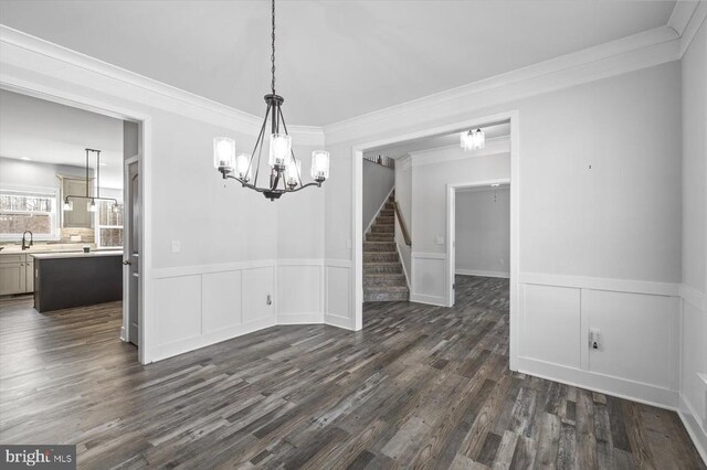 unfurnished dining area featuring an inviting chandelier, sink, crown molding, and dark hardwood / wood-style floors