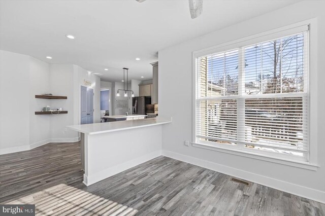 kitchen featuring pendant lighting, stainless steel fridge, dark hardwood / wood-style flooring, and kitchen peninsula