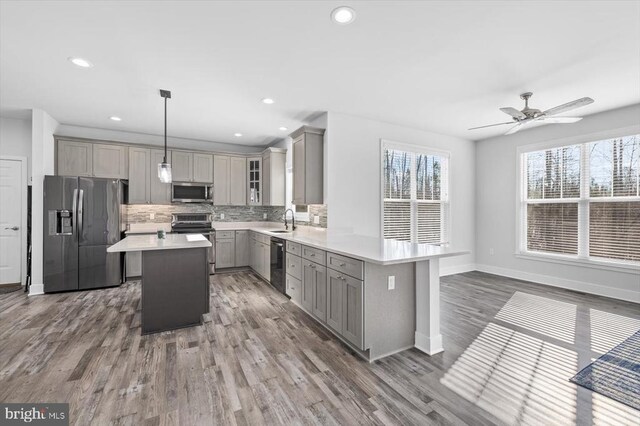 kitchen featuring sink, gray cabinetry, decorative light fixtures, a kitchen island, and stainless steel appliances