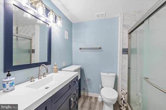 bathroom featuring walk in shower, wood-type flooring, toilet, and vanity