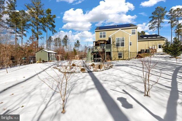 snow covered property featuring a storage unit, a deck, and solar panels