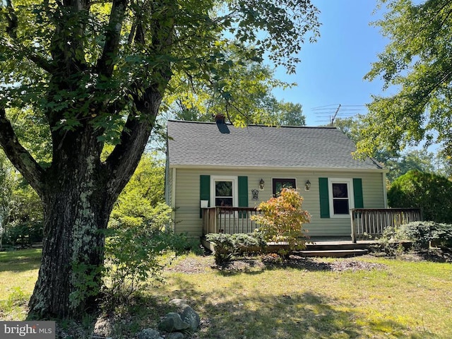 view of front of property with a front lawn, a chimney, and a shingled roof