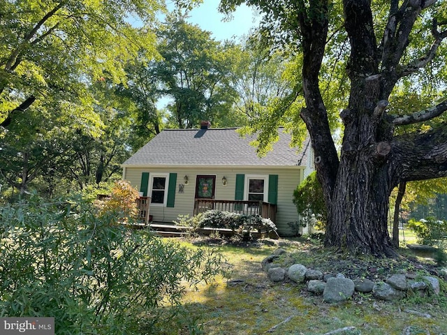 view of front facade featuring a shingled roof and a deck