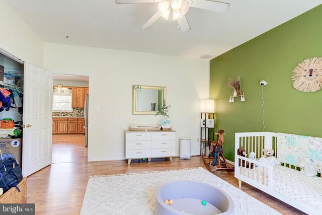 bedroom featuring ceiling fan, sink, stainless steel refrigerator, and light hardwood / wood-style flooring